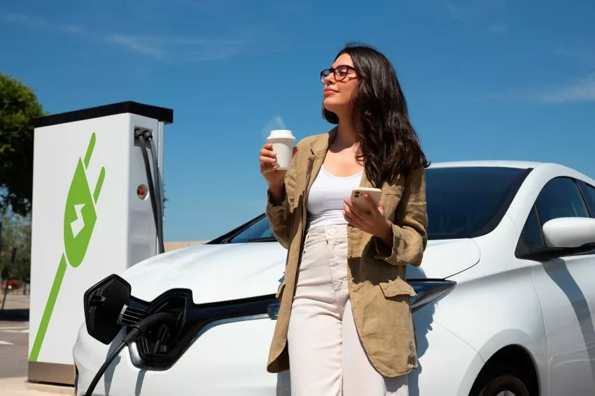 mulher bebendo café ao lado de um carro