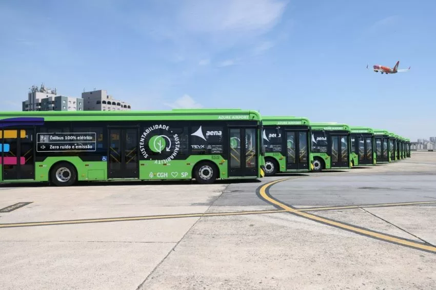 Dez ônibus elétricos são vistos na pista de Congonhas com avião decolando ao fundo