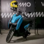 Moto elétrica da Vammo com um capacete amarelo e o logo da 99 no guidão