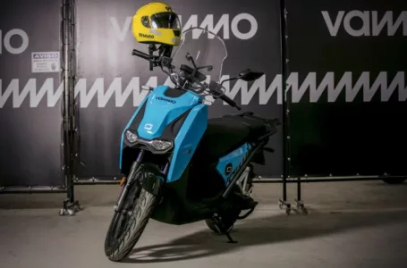Moto elétrica da Vammo com um capacete amarelo e o logo da 99 no guidão