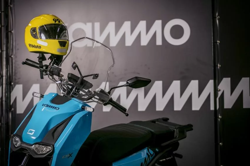 Moto elétrica da Vammo com um capacete amarelo e o logo da 99 no guidão