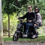 Casal passeia de bike elétrica em área arborizada