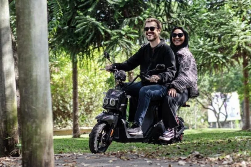Casal passeia de bike elétrica em área arborizada