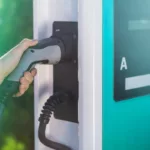 Mão masculina segura plugue em equipamento de recarga de veículos elétricos