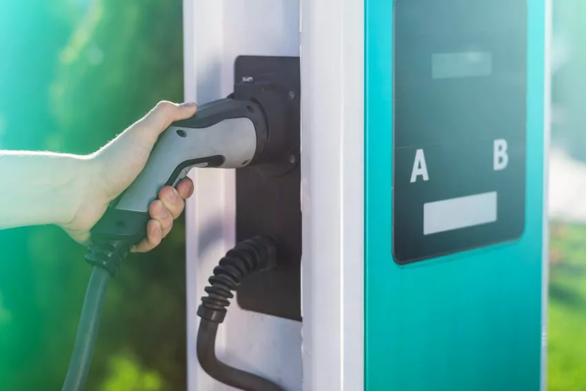 Mão masculina segura plugue em equipamento de recarga de veículos elétricos
