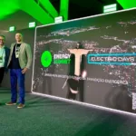 Dois executivos posam para foto ao lado de painel do Energy Summit e do Electric Days