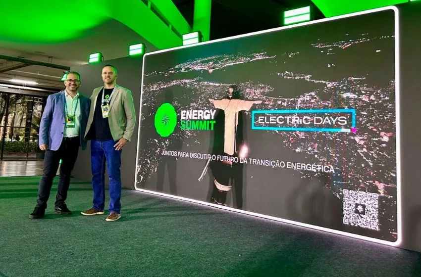 Dois executivos posam para foto ao lado de painel do Energy Summit e do Electric Days