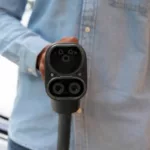 Homem segura conector do tipo CCS2 de frente para a câmera