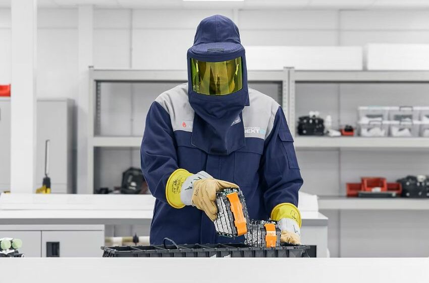 Pesquisador, usando equipamento EPI, trabalha com bateria em bancada
