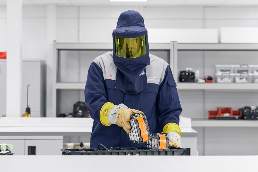 Pesquisador, usando equipamento EPI, trabalha com bateria em bancada