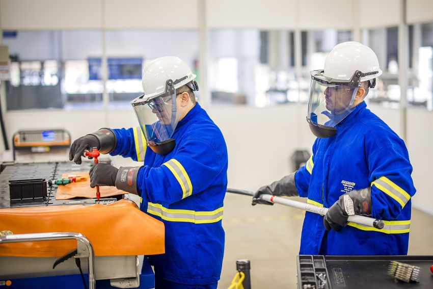 Dois homens trabalham na bateria com equipamentos de proteção
