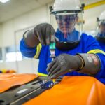 Funcionário com EPI usa chave de fenda em parafuso da bateria