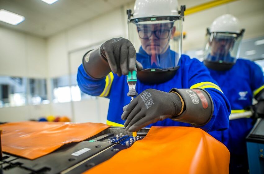 Funcionário com EPI usa chave de fenda em parafuso da bateria