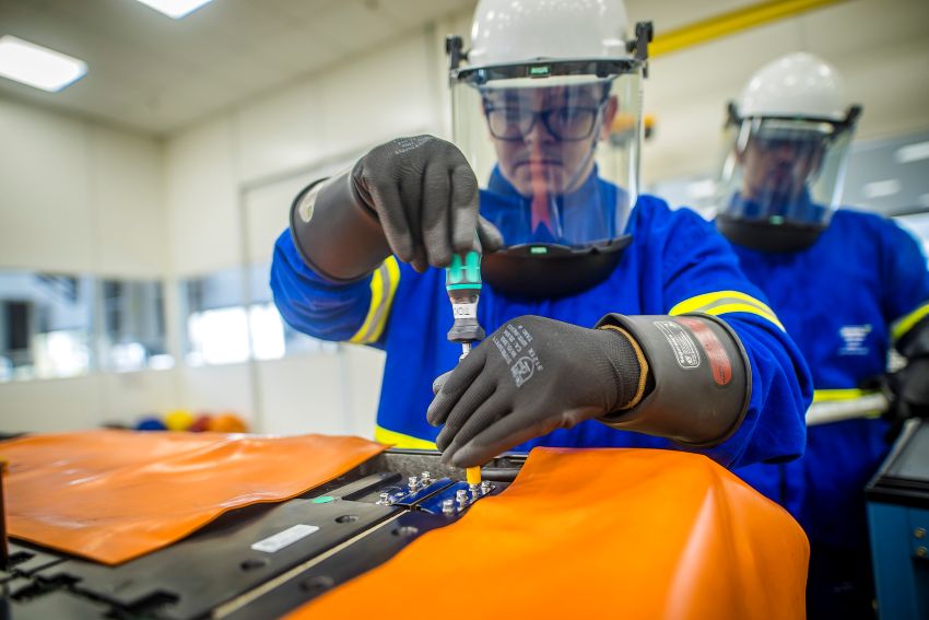 Funcionário com EPI usa chave de fenda em parafuso da bateria