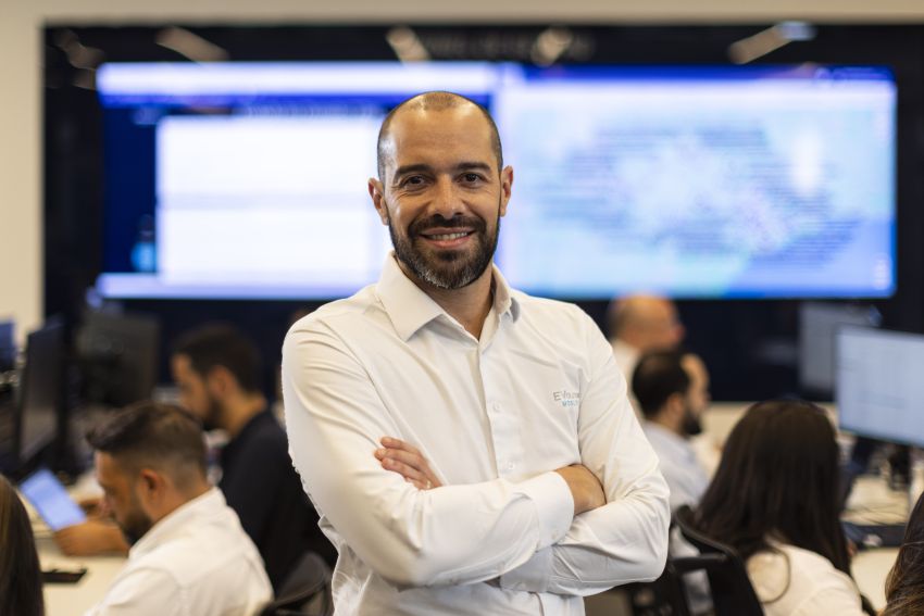 Lucas Zanon está de braços cruzados em ambiente empresarial