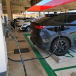 Veículo preto estacionado em um eletroposto fazendo o carregamento
