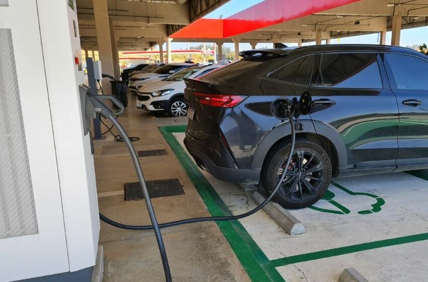Veículo preto estacionado em um eletroposto fazendo o carregamento