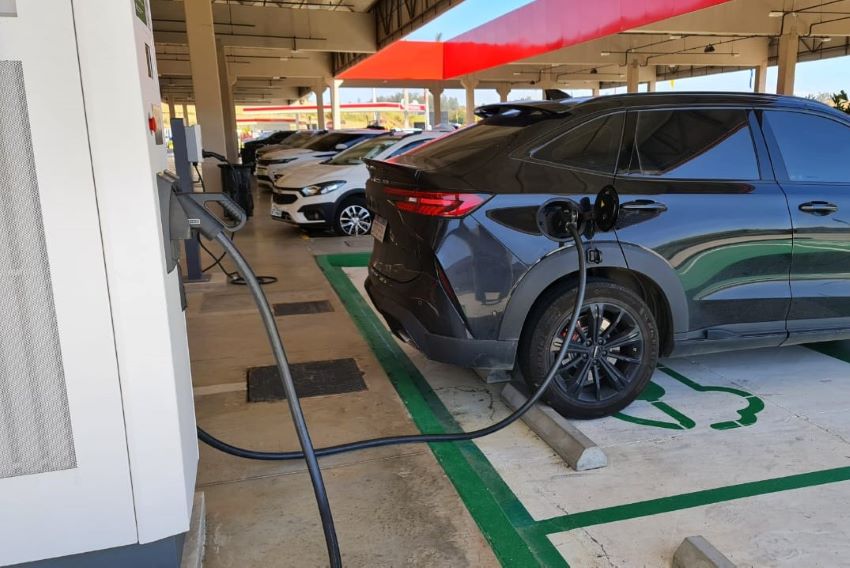 Veículo preto estacionado em um eletroposto fazendo o carregamento