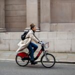 Imagem mostra uma jovem mulher andando de bicicleta na cidade