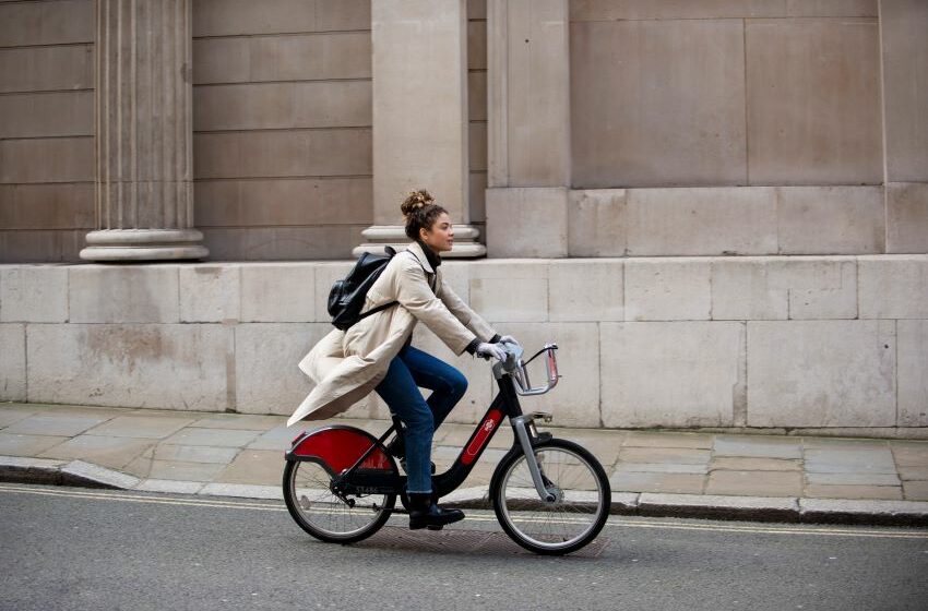 Imagem mostra uma jovem mulher andando de bicicleta na cidade
