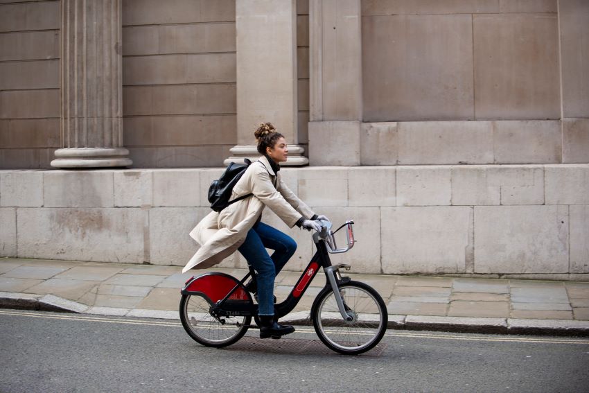 Imagem mostra uma jovem mulher andando de bicicleta na cidade