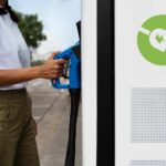 Mulher se aproxima de estação de recarga de veículos elétricos