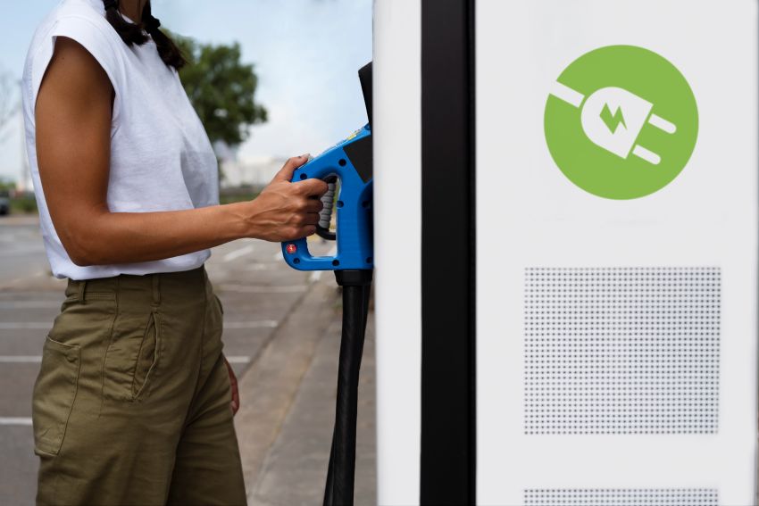 Mulher se aproxima de estação de recarga de veículos elétricos