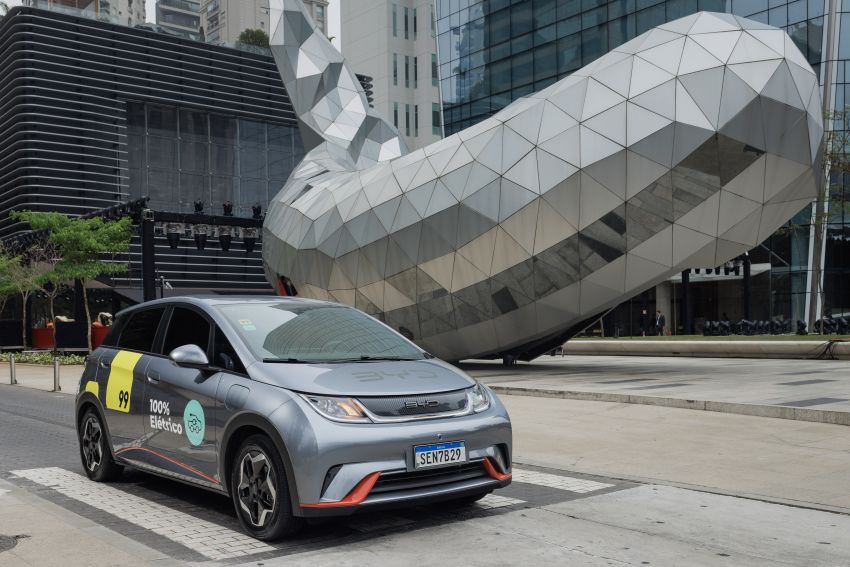BYD Dolphin com adesivo da 99 é fotografado em frente a escultura