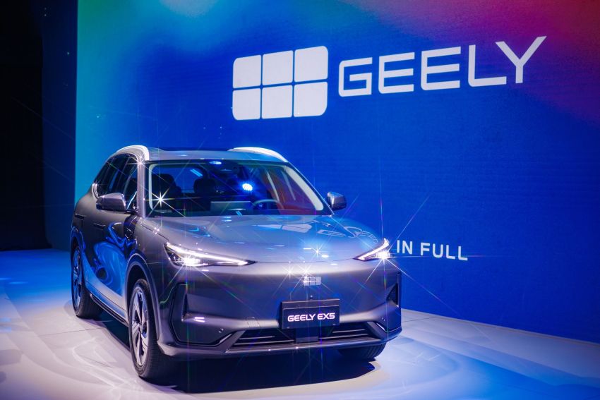 Carro EX5 exposto em frente a painel azul com a logotipo da Geely