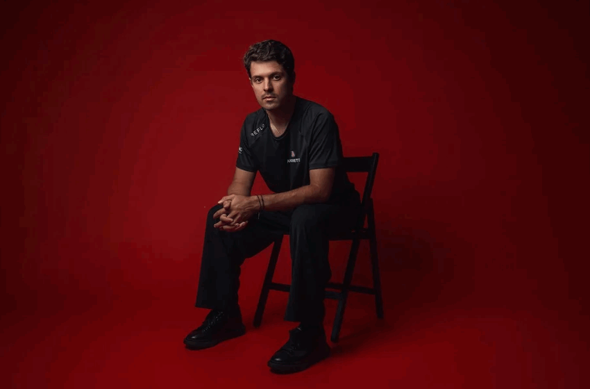 Felipe Drugovich está sentado em uma cadeira, em frente a um fundo vermelho