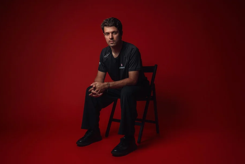 Felipe Drugovich está sentado em uma cadeira, em frente a um fundo vermelho
