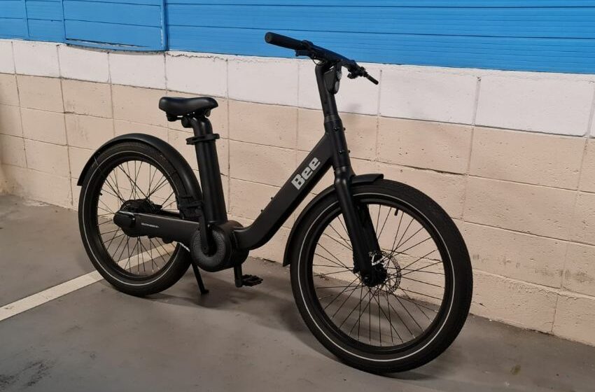 Bike elétrica amparada em parede azul e cinza