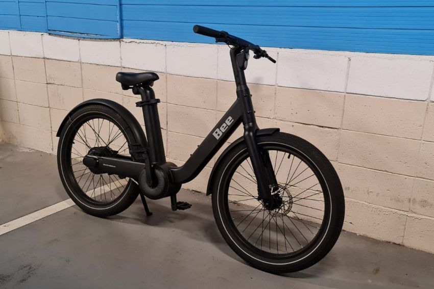 Bike elétrica amparada em parede azul e cinza