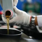 Mecânico despeja lubrificante em compartimento de carro