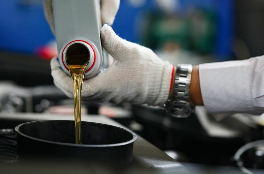 Mecânico despeja lubrificante em compartimento de carro