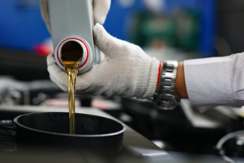 Mecânico despeja lubrificante em compartimento de carro