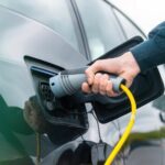 Homem conecta plugue de recarga em carro elétrico