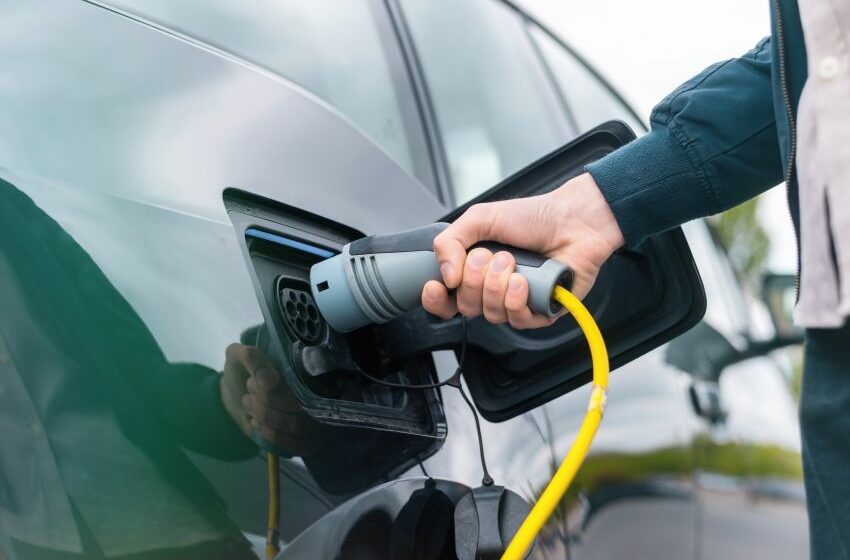 Homem conecta plugue de recarga em carro elétrico