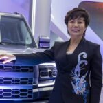 Stella Li posa para foto ao lado de carro da Denza