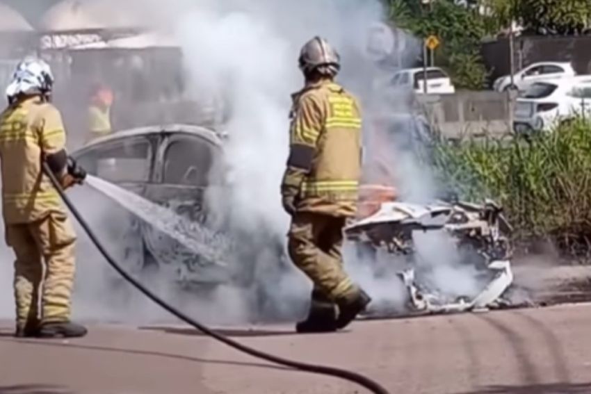 Bombeiros jogam água em carro incendiado na rua
