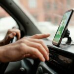 Motorista manuseia aplicativo em smartphone enquanto dirige