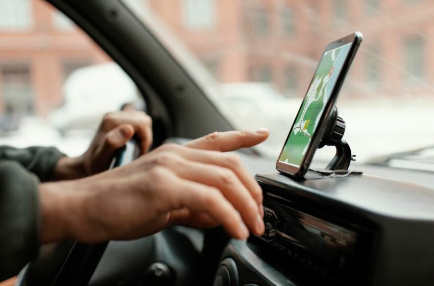 Motorista manuseia aplicativo em smartphone enquanto dirige