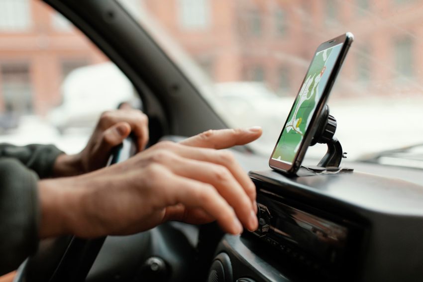 Motorista manuseia aplicativo em smartphone enquanto dirige