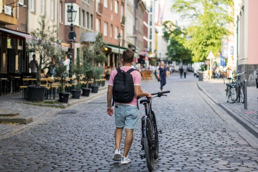 Homem leva bicicleta por ruas de Amsterdam