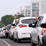 Motoristas levantam os braços em comboio com buzinaço em Brasília